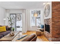 Cozy living room featuring a brick fireplace, hardwood floors, and a sliding glass door to the exterior at 350 Arapahoe Ave # 10, Boulder, CO 80302