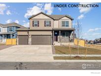 Two-story home with stone accents, covered porch, three-car garage, and fresh lawn at 4107 Marble Dr, Mead, CO 80504