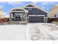 Charming single Gathering home with blue siding and stone accents, covered front porch, and attached garage at 490 N Ider Way, Aurora, CO 80018