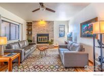 Comfortable living room featuring stylish sofas, stone fireplace, and geometric-patterned rug at 525 Manhattan Dr # 104, Boulder, CO 80303