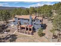 Stunning blue home showcasing a two-tiered deck surrounded by lush greenery and mountain views at 820 Peakview Rd, Boulder, CO 80302