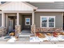 Charming townhome with a welcoming front porch, stone accents, and fresh landscaping at 891 Winding Brook Dr, Berthoud, CO 80513