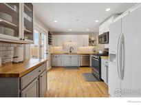 Updated kitchen with hardwood floors, gray cabinets, stainless steel appliances, and subway tile backsplash at 920 W 1St Ave, Broomfield, CO 80020