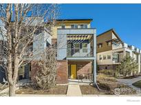 Modern home with brick accents, yellow door, and balcony featuring metal railings at 11225 Colony Cir, Broomfield, CO 80021