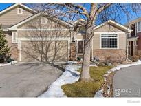 Inviting front exterior featuring stone accents, a well-manicured lawn, and attached two car garage at 13832 Legend Way # 102, Broomfield, CO 80023