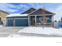 Charming blue home featuring a covered front porch, stone accents, and a two-car garage, perfect for suburban living at 2112 Cadman St, Berthoud, CO 80513