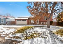 Charming split-level home featuring a two-car garage, brick accents, and a well-manicured lawn with mature tree at 2962 E 96Th Pl, Thornton, CO 80229