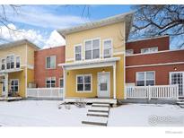 Charming yellow townhome featuring a covered porch and winter snow in a cozy neighborhood setting at 3380 Folsom St # 115, Boulder, CO 80304