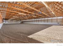 Spacious indoor horse arena featuring high ceilings, ample lighting, and well-maintained sand footing at 3401 Meining Rd, Berthoud, CO 80513