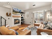 Inviting living room featuring a fireplace, a large TV, and a sliding door to a balcony with an expansive view at 7841 W 55Th Ave, Arvada, CO 80002