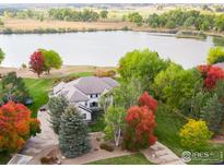 Stunning aerial view of a beautiful home nestled among colorful trees, with a serene lake in the backdrop at 10667 E Goose Haven Dr, Lafayette, CO 80026