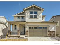 Charming two-story home featuring a covered porch and a two-car garage with stone accents at 170 Fremont Ct, Brighton, CO 80601