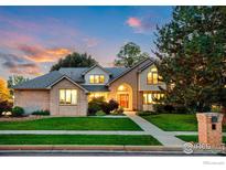 Charming home with brick facade, lush lawn, and mature trees under a colorful sunset sky at 2245 Ridgeview Way, Longmont, CO 80504