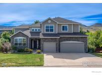 Charming two-story home with stone accents, a well-manicured lawn, and a three-car garage at 5385 Dunraven Cir, Golden, CO 80403