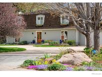 Charming two-story home featuring a well-manicured front yard with mature trees and flowering bushes at 7034 Indian Peaks Trl, Boulder, CO 80301