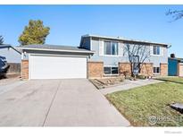 Split-level home with a two-car garage, light blue siding and a brick facade at 11671 Garfield St, Thornton, CO 80233