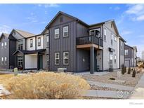 Modern townhome with dark gray siding and a second-story balcony, complemented by tidy landscaping at 167 Ambrose St, Erie, CO 80516