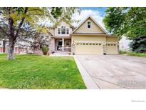 Charming two-story home featuring a three-car garage, stone accents, a manicured lawn, and mature trees at 1872 W 130Th Dr, Westminster, CO 80234