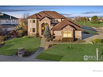Charming two-story home featuring a beautiful lawn, stone accents, and a welcoming walkway at 1949 Wasach Dr, Longmont, CO 80504