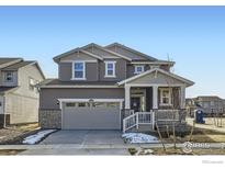 Charming two-story home with a covered porch and gray siding, complemented by a two car garage at 4846 Astor Pl, Brighton, CO 80601
