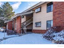 Multi-story condo with red brick and off-white stucco, snowy landscaping, and a stairway entrance at 595 Manhattan Dr # 203, Boulder, CO 80303