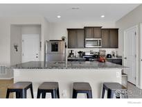 Modern kitchen features a granite countertop island with seating and stainless steel appliances at 7014 Fall River Dr, Frederick, CO 80530