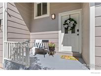 Inviting front porch featuring a comfortable chair and a charming floral wreath on the white front door at 8087 Meadowdale Sq, Niwot, CO 80503