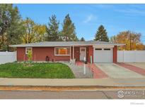 Charming red brick ranch home with a well-maintained front yard, driveway, and attached garage at 1211 16Th Ave, Longmont, CO 80501