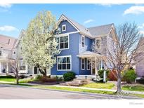 Charming two-story blue home with a blossoming tree in the front yard, creating a picturesque curb appeal at 1526 Haystack Way, Lafayette, CO 80026