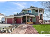 Inviting two-story home with stone accents, a covered porch, and a three-car garage at 2100 Breckenridge Dr, Berthoud, CO 80513