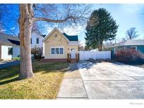 Charming home with a yellow exterior, a large front yard, and a concrete driveway at 324 Francis St, Longmont, CO 80501