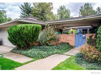 Charming home featuring a covered carport, brick entryway, and a welcoming blue gate amidst lush greenery at 390 Inca Pkwy, Boulder, CO 80303