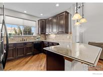 Modern kitchen with dark cabinetry, granite countertops, and stainless steel appliances at 4822 Raven Run, Broomfield, CO 80023