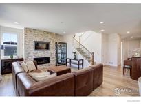 Cozy living room featuring a stone fireplace, leather sofa, and staircase at 55 Morgan S Cir, Erie, CO 80516