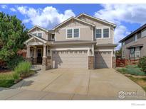 Charming two-story home featuring a three-car garage and inviting stone-accented entryway at 15453 E 109Th Ave, Commerce City, CO 80022