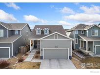 Charming home featuring a two-car garage, grey siding, dormer windows, and a well-maintained front yard at 2719 Tallgrass Ln, Berthoud, CO 80513