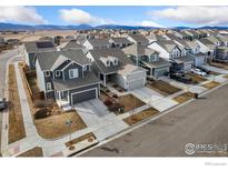 Street view of gray two-story home with manicured lawn and a two-car garage in a neighborhood of similar homes at 2719 Tallgrass Ln, Berthoud, CO 80513