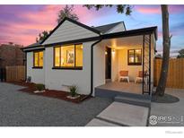 Charming white brick home featuring a covered porch, dark trim, and manicured landscaping at 450 S Decatur St, Denver, CO 80219