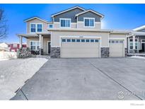 Charming two-story home featuring a three-car garage and stone accents, set against a snowy landscape at 5482 Wetlands Dr, Frederick, CO 80504