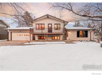 Charming two-story home with a two-car garage and balcony is surrounded by a snow-covered lawn at 5564 Colt Dr, Longmont, CO 80503