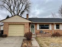 Charming single-story brick home featuring an attached garage, quaint front porch, and well-maintained landscaping at 6 Sunset Cir, Longmont, CO 80501