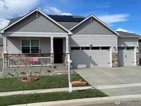 Charming home featuring stone accents, a welcoming front porch, a three-car garage, and solar panels at 1431 Vantage Pkwy, Berthoud, CO 80513