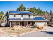 Charming two-story home featuring solar panels, covered porch, manicured lawn, and attached garage at 1740 Bear Mountain Dr, Boulder, CO 80305