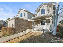 Charming two-story home featuring a brick facade and covered front porch, exuding curb appeal at 1750 Little Bear Dr, Longmont, CO 80504