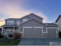 Charming two-story home featuring a three car garage and a welcoming front porch with stone accents at 1931 Rannoch Dr, Longmont, CO 80504