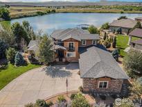 Stunning lakefront home featuring a circular driveway, professional landscaping, and stone accents at 5763 Pelican Shores Dr, Longmont, CO 80504