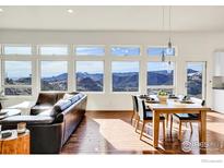 Bright living room with hardwood floors, leather sofa, dining table, and expansive windows with mountain views at 6191 Sunshine Canyon Dr, Boulder, CO 80302