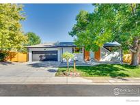 Charming single-story home with a lush green lawn, mature trees and a modern, attached two-car garage at 7022 Quay St, Arvada, CO 80003