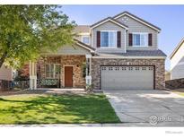 Charming two-story home featuring a brick facade, well-manicured lawn, and an inviting covered front porch at 14828 E 118Th Pl, Commerce City, CO 80603