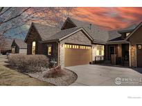 Charming exterior elevation of a house with stone accents and a two-car garage at sunset at 2238 Calais Dr # B, Longmont, CO 80504